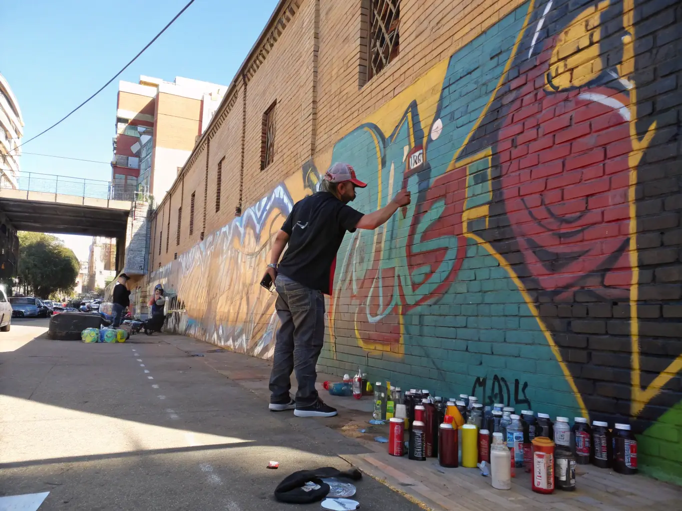A CRAZY SPRAY artist demonstrating advanced aerosol techniques at a public event, with a crowd of onlookers observing and engaging with the artist.