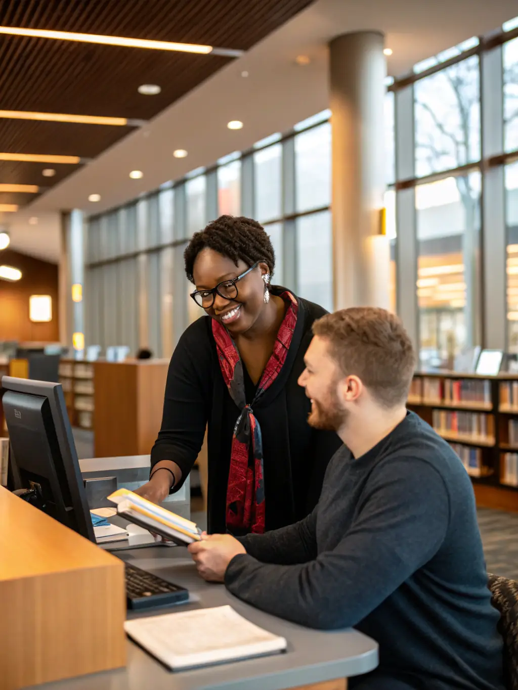 A librarian assisting a senior citizen with using a computer at LECTURE POUR TOUS, providing digital literacy support and guidance.